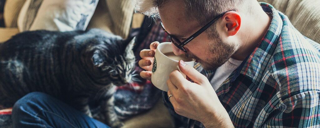 Man drinking coffee with a cat