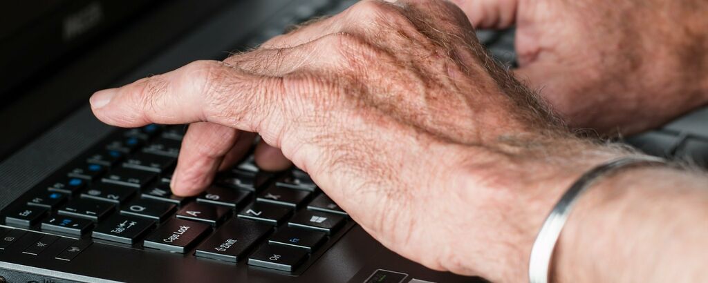 Old hands typing laptop